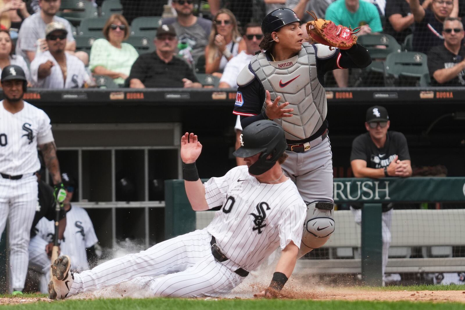 Chicago White Sox's Chase Meidroth, bottom, scores on a one-run single by Austin Slater as Cleveland Guardians catcher Bo Naylor looks to the field during the fifth inning of a baseball game in Chicago, Sunday, July 13, 2025. (AP Photo/Nam Y. Huh)