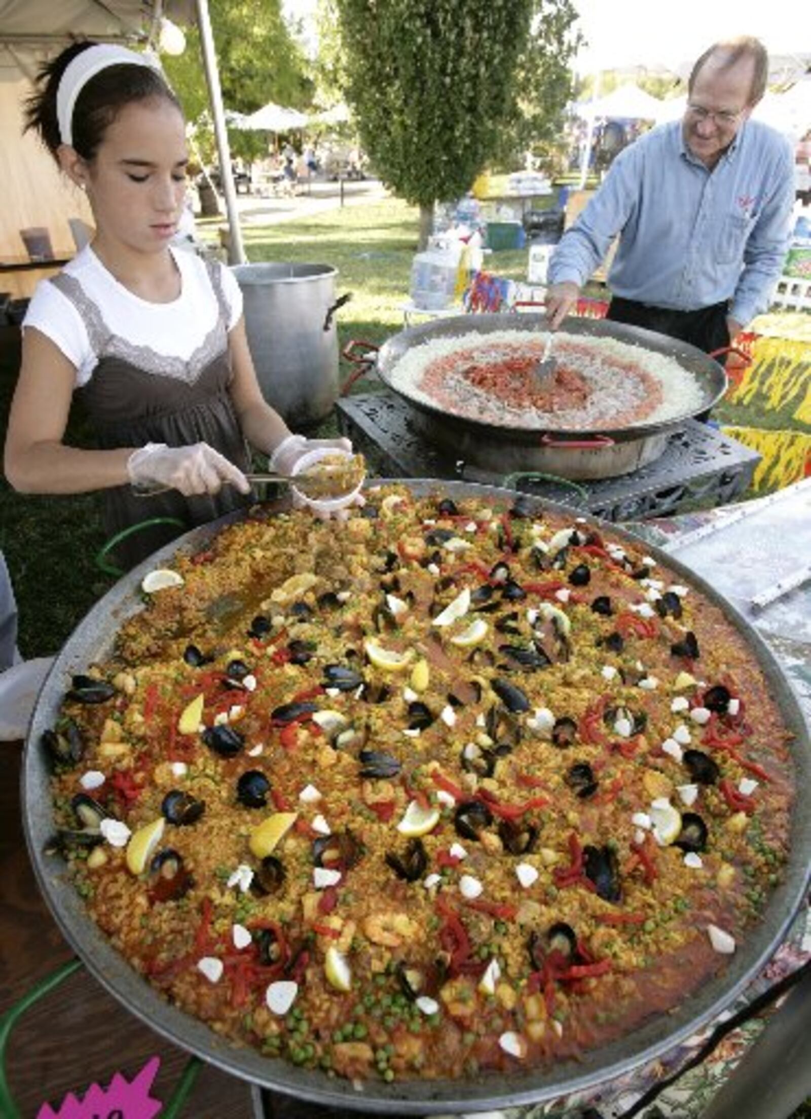 Archive photo — Anna Castro, left, served Paella as El Meson chef Mark Abbott started another paella pan featuring seafood and garlic at the 2007 Garlic Festival at Cox Arboretum Metro Park.( Photo: Ty Greenlees)