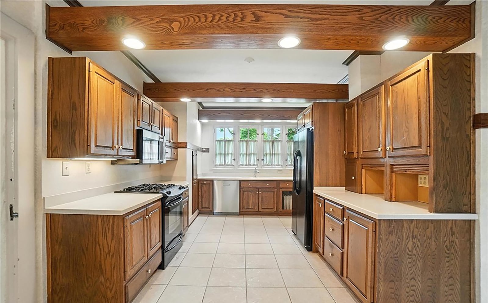 The kitchen has beamed ceilings, wood cabinets and tile flooring. It also has a breakfast nook and all appliances.