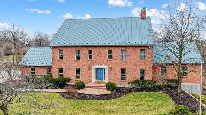 The brick colonial style two story has a copper roof and is heavily landscaped with a pond on the property.