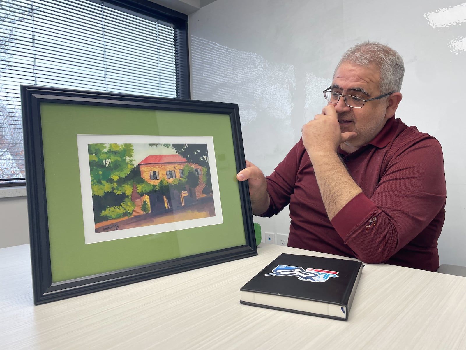 Youssef Elzein holds up artwork depicting his grandparents' home in southern Lebanon.