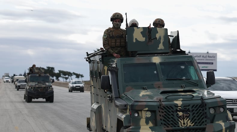 Syrian government soldiers stand on their armoured vehicle, as their convoy passes on a highway to the Deir Hafer village for a possible escalation fighting with the Kurdish fighters, in eastern Aleppo, Syrian, Wednesday, Jan. 14, 2026. (AP Photo/Ghaith Alsayed)