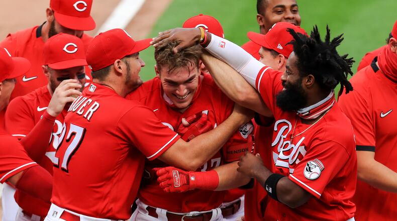 Cincinnati Reds' Trevor Bauer, left, hugs Tyler Stephenson, center, after Stephenson hit a walkoff two-run home run in the seventh inning while Brian Goodwin, right, reacts during a baseball game against the Pittsburgh Pirates in Cincinnati, Monday, Sept. 14, 2020. (AP Photo/Aaron Doster)