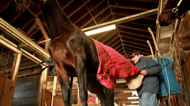 Tom Horner, a horse trainer at the Montgomery County Fairgrounds, changes the blanket on one of his horses in the barn to keep him warm during a cold snap. File photo