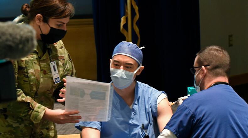 Maj. Richard Brocksmith, an 88th Medical Group nurse anesthetist, listens to instructions from Maj. Holly Holko, 88 MDG medical services flight commander, while receiving the COVID-19 vaccine from Dale Guinther, an 88 MDG nurse, at Wright-Patterson Air Force Base on Jan. 4. Portions of this photo have been altered for security reasons. U.S. AIR FORCE PHOTO/TY GREENLEES