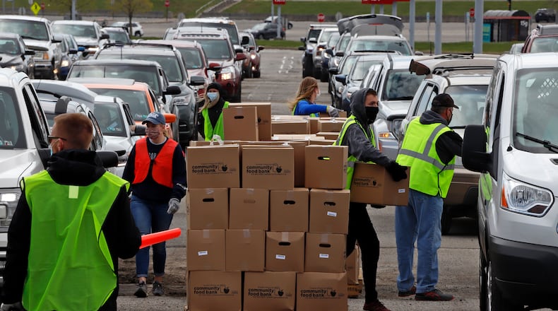 Using part of the Pittsburgh International Airport parking lot that has been left vacant by the COVID-19 pandemic, volunteers from the Greater Pittsburgh Community Food Bank load boxes of food into cars during a drive-up food distribution Wednesday. (AP Photo/Gene J. Puskar)