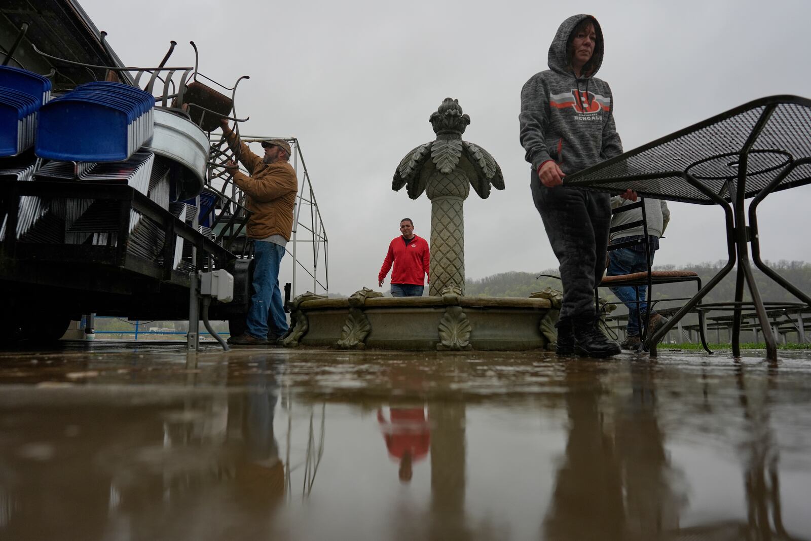 Drew's on the River Sports Bar and Grill manager, Carrie Haines, right, Frank left, and Steve Schmidt son of owner Ron Schmidt, center load furnature on to trailer in the rain as the Ohio River rises, Friday, April 4, 2025, in Cincinnati. (AP Photo/Carolyn Kaster)