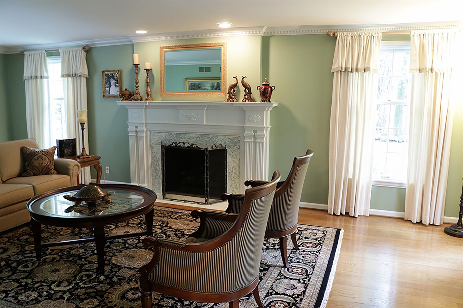 The formal living room has a gas fireplace with dentil fluted wood mantel and marble surround that matches the foyer flooring. CONTRIBUTED PHOTO BY KATHY TYLER
