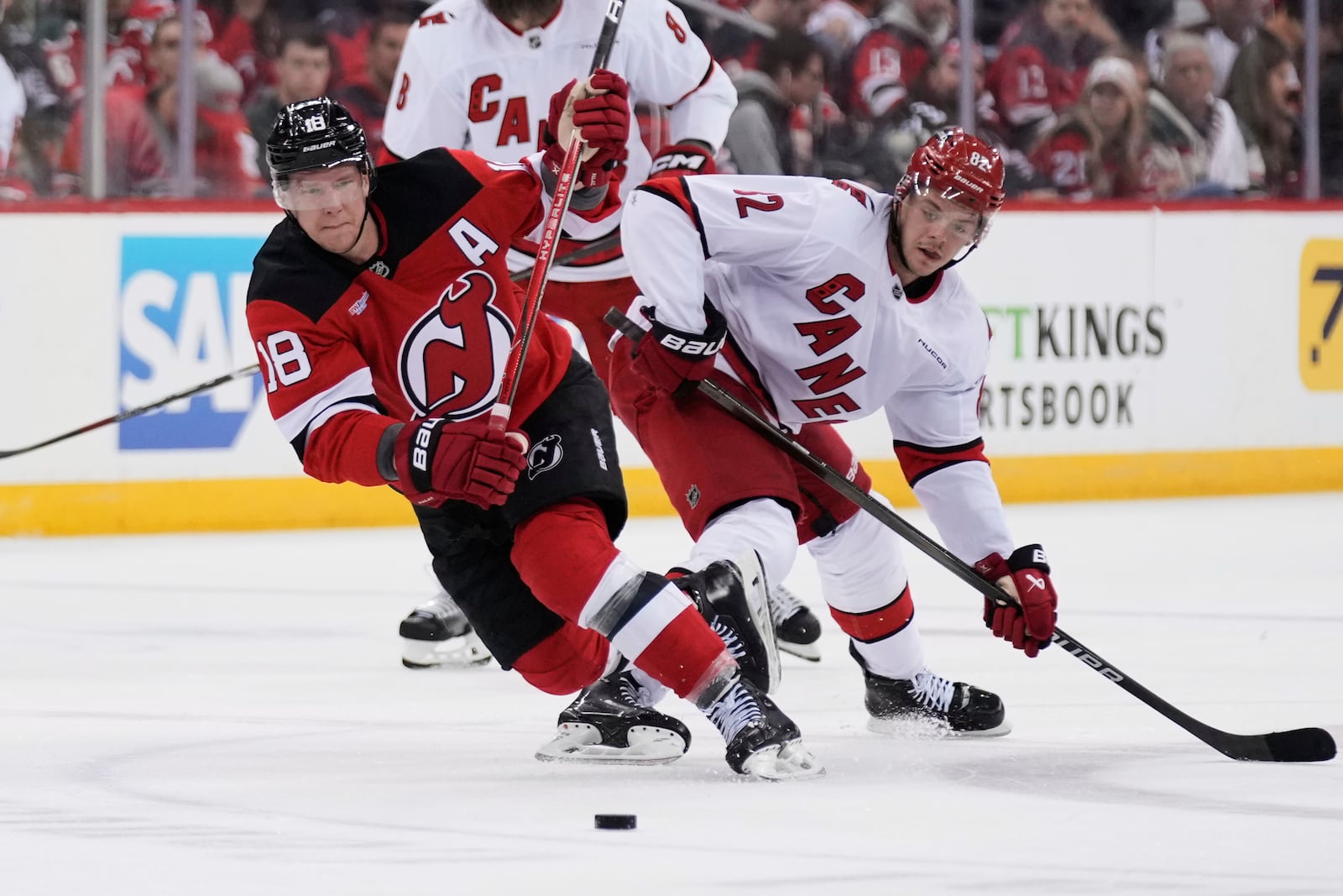 New Jersey Devils' Ondrej Palat, left, and Carolina Hurricanes' Jesperi Kotkaniemi compete for the puck during the first period of Game 4 of an NHL hockey first-round series, Sunday, April 27, 2025, in Newark, N.J. (AP Photo/Seth Wenig)