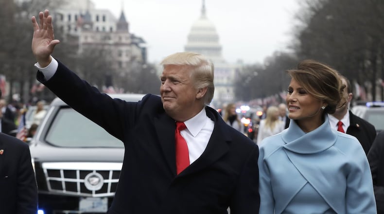 President Donald Trump waves as he walks with first lady Melania Trump during the inauguration parade on Pennsylvania Avenue in Washington. (AP Photo/Evan Vucci)