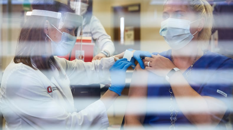 Pharmacist Emily Vrontos injects Andrea Yagodich, a respiratory therapist, with the Pfizer-BioNTech COVID-19 vaccine at The Ohio State University Wexner Medical Center in Columbus, Ohio, Tuesday, Dec. 15, 2020. Vaccines are rolling out to health workers now and will reach the arms of the rest of us by spring. (Brian Kaiser/The New York Times)