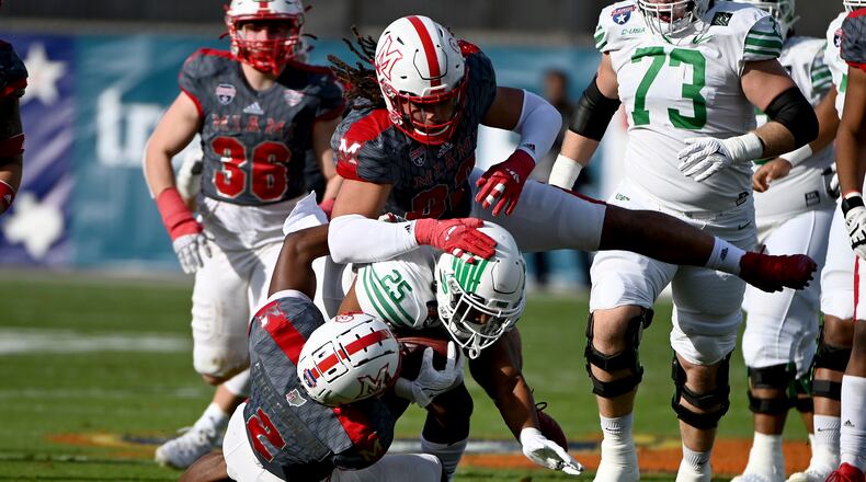 Miami defensive back Cecil Singleton (2) and defensive lineman Kameron Butler (82) tackle North Texas running back Ikaika Ragsdale (25) in the first half of the Frisco Football Classic NCAA college football game in Frisco, Texas, Thursday, Dec. 23, 2021. (AP Photo/Matt Strasen)