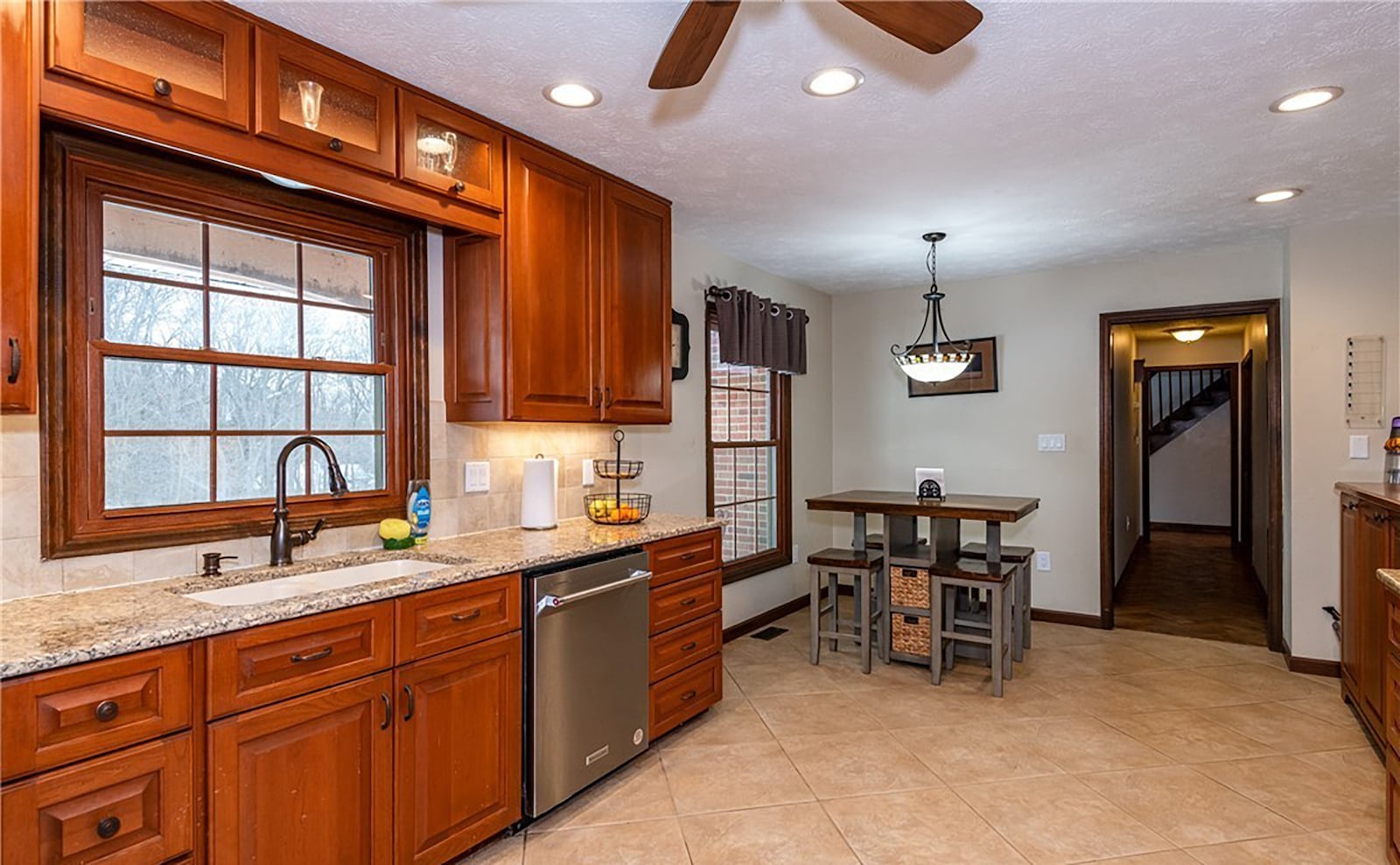 The updated kitchen has wood cabinets, granite countertops and a tile backsplash. It has tile flooring, a breakfast nook, ceiling fan and decorative chandelier and recessed lighting. It has updated stainless appliances. CONTRIBUTED
