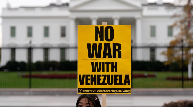 A demonstrator holds a sign while protesting outside of the White House in Washington, Saturday, Nov. 15, 2025. (AP Photo/Jose Luis Magana)