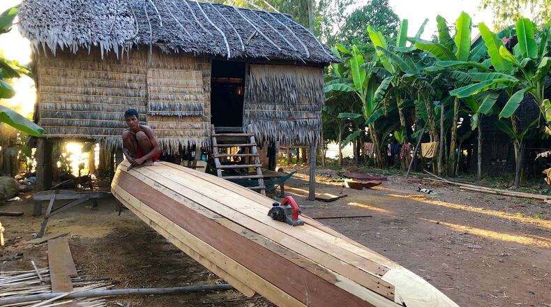 A young man builds a boat from local timber, hand-cutting each plank to fit the curved frame and rising prow that is customary to fishing boats on the Mekong River in central Cambodia. (Andrew Evans/Chicago Tribune/TNS)