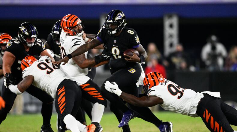 Baltimore Ravens quarterback Lamar Jackson, center, scrambles against Cincinnati Bengals' Zach Carter, right, during the second half of an NFL football game, Sunday, Oct. 9, 2022, in Baltimore. (AP Photo/Nick Wass)