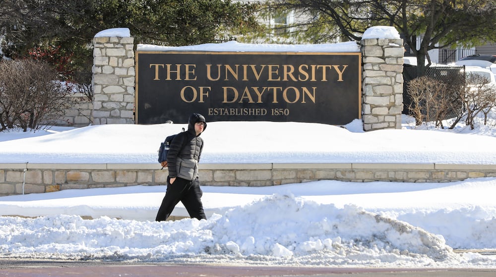 A man walks by a University of Dayton sign at the intersection of East Stewart Street and Brown Street on Tuesday, Jan. 28 in Dayton. BRYANT BILLING/STAFF