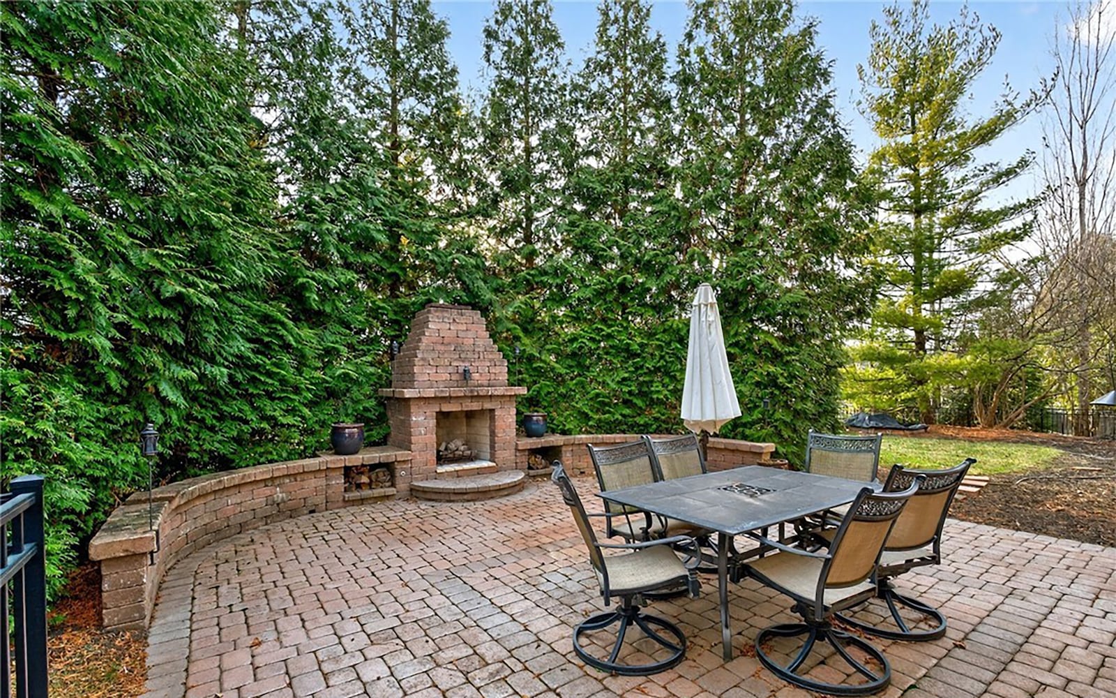 The backyard paver patio has a built in fireplace and a half wall. The yard is fully fenced and is lined with mature trees. CONTRIBUTED