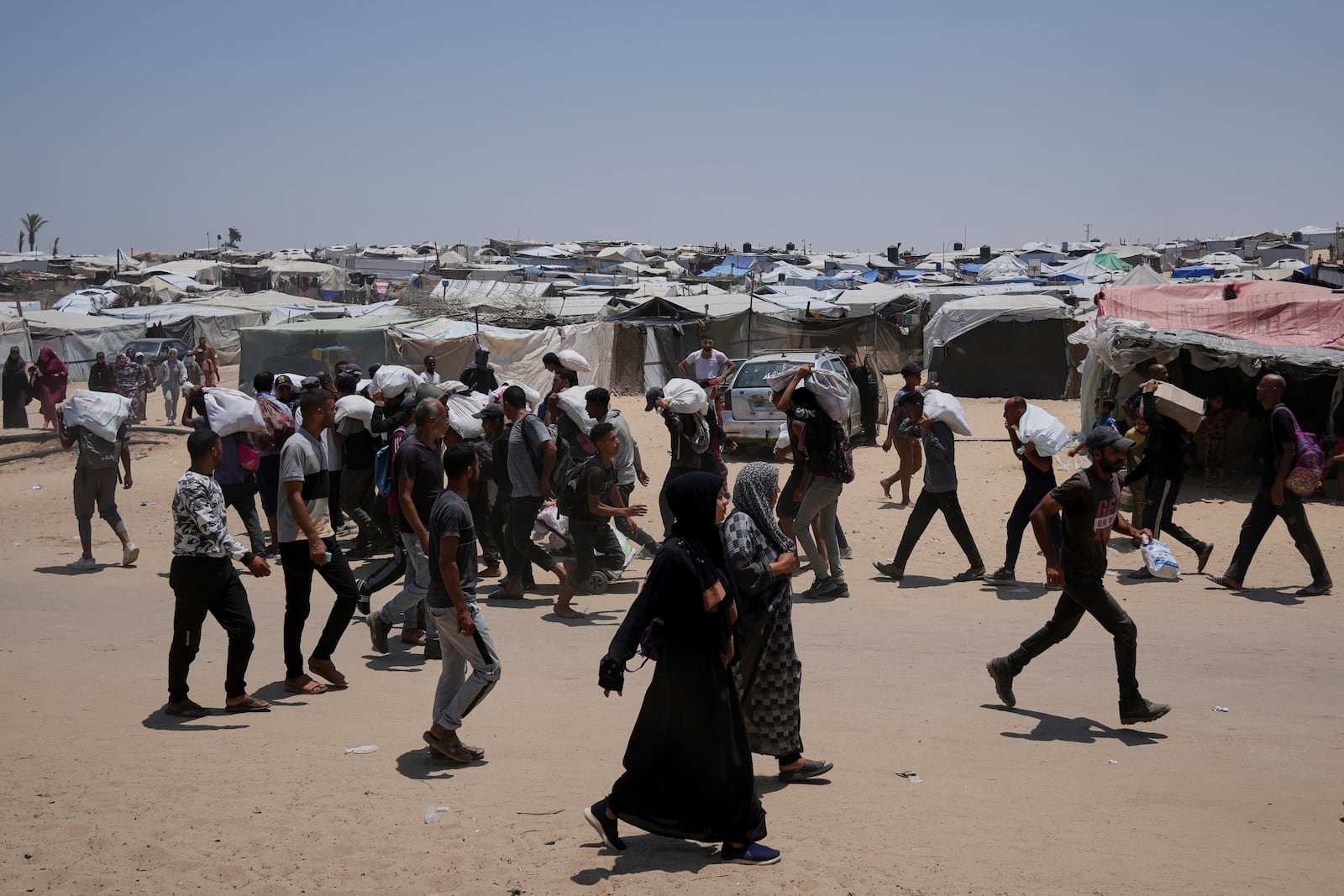 Palestinians carry bags containing food and humanitarian aid packages delivered by the Gaza Humanitarian Foundation, a U.S.-backed organization, in Rafah, southern Gaza Strip, Sunday, June 8, 2025. (AP Photo/Abdel Kareem Hana)