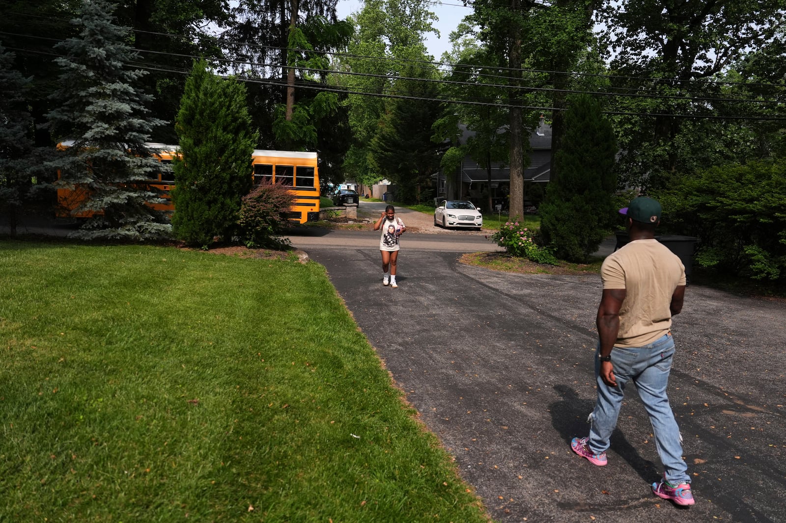Evan Polk, right, walks to greet his daughter, Jordyn Polk, 13, from the bus after school in Secane, Pa., Thursday, June 5, 2025. (AP Photo/Matt Slocum)