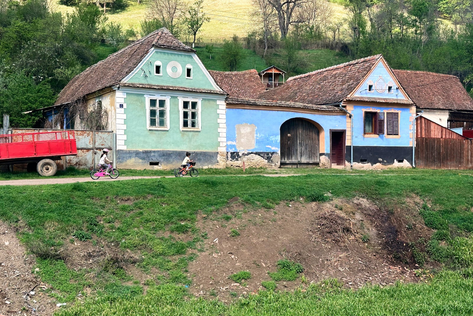 Children ride bicycles in the village of Floresti, in Romania's central Transylvania region, Thursday, April 24, 2025. (AP Photo/Stephen McGrath)