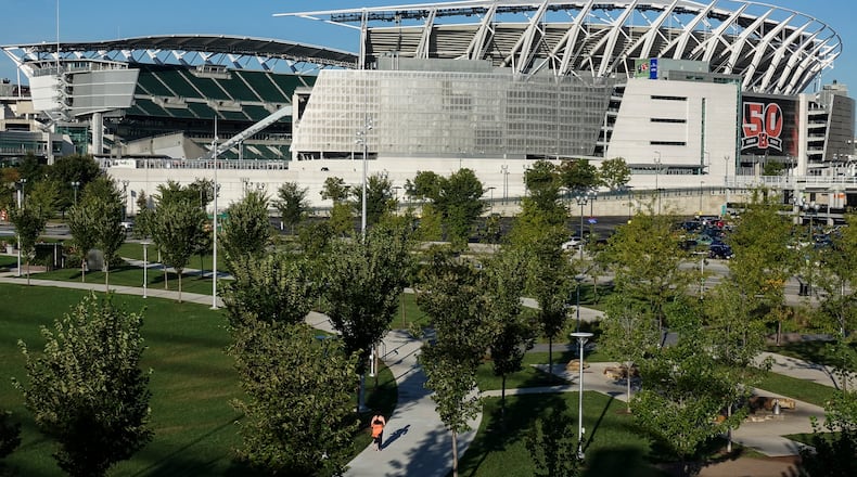 FILE - A pedestrian runs through Smale Park on the Ohio River front near Paul Brown Stadium, home of the Cincinnati Bengals NFL Football team, as a celebratory 50th anniversary banner is displayed outside its gates, Thursday, Sept. 28, 2017, in Cincinnati. There are 23 venues bidding to host soccer matches at the 2026 World Cup in the United States, Mexico and Canada. (AP Photo/John Minchillo, File)