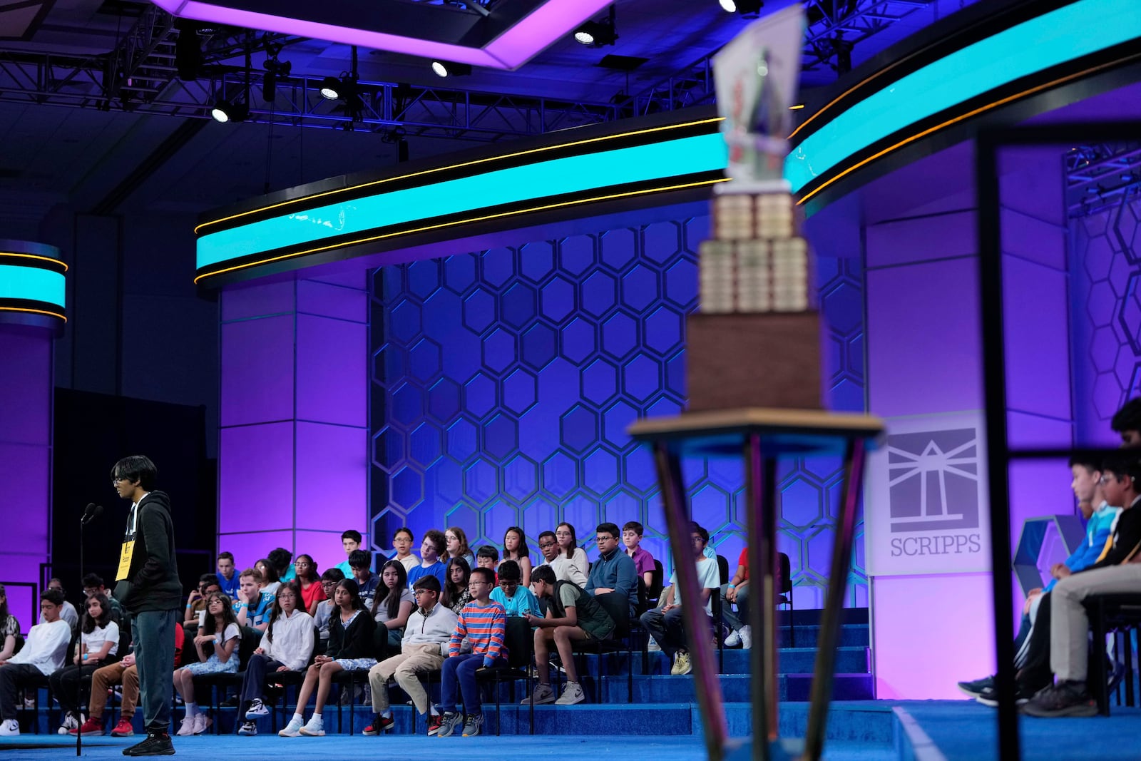 With the trophy in the foreground, Faizan Zaki, 13, of Dallas, competes in the finals of the Scripps National Spelling Bee, Thursday, May 29, 2025, in Oxon Hill, Md. (AP Photo/Julia Demaree Nikhinson)