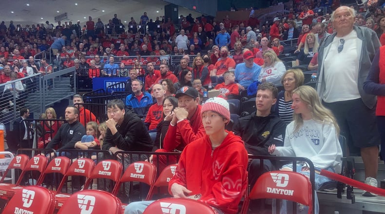 Dayton recruit Mike Sharavjamts sits behind the bench during a game against Davidson on Saturday, March 5, 2022, at UD Arena. David Jablonski/Staff