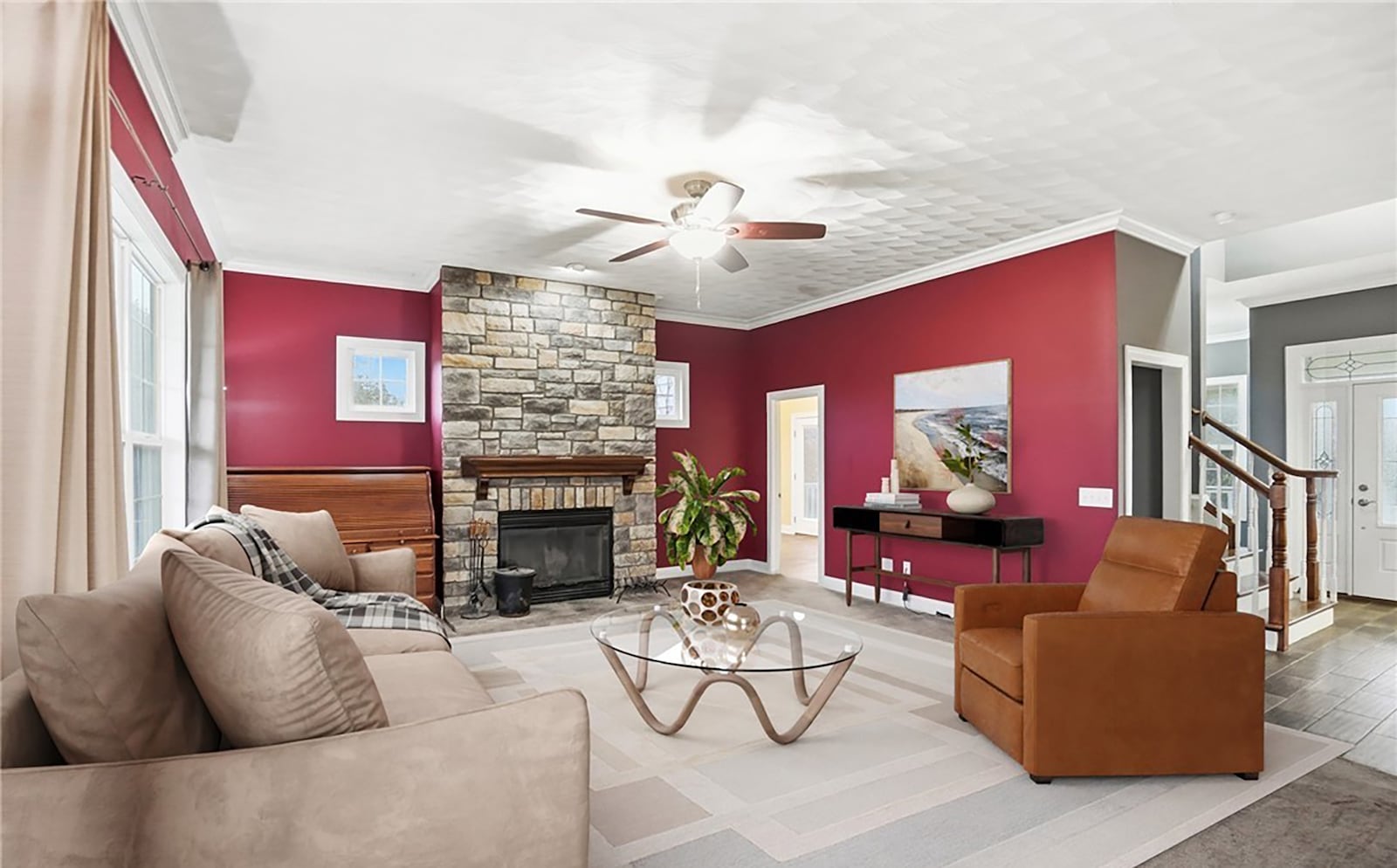 The living room features a stacked stone fireplace, ceiling fan, and carpeting. It is open to the foyer and the kitchen. CONTRIBUTED