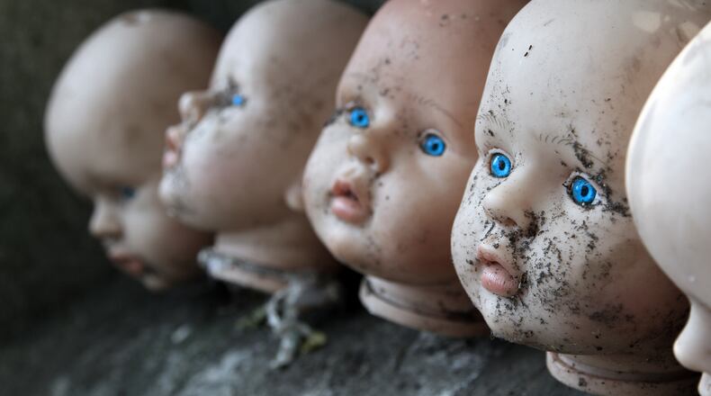 Several children head doll with blue eyes lie in the old yard - scary stories - fear - a fairy tale. Photo: Shutterstock