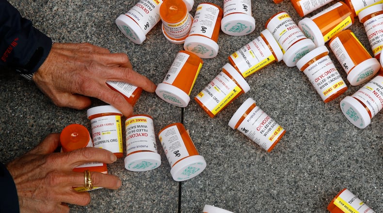 A protester gathers containers that look like OxyContin bottles at an anti-opioid demonstration in front of the U.S. Department of Health and Human Services headquarters in Washington on April 5, 2019. (AP Photo/Patrick Semansky, File)