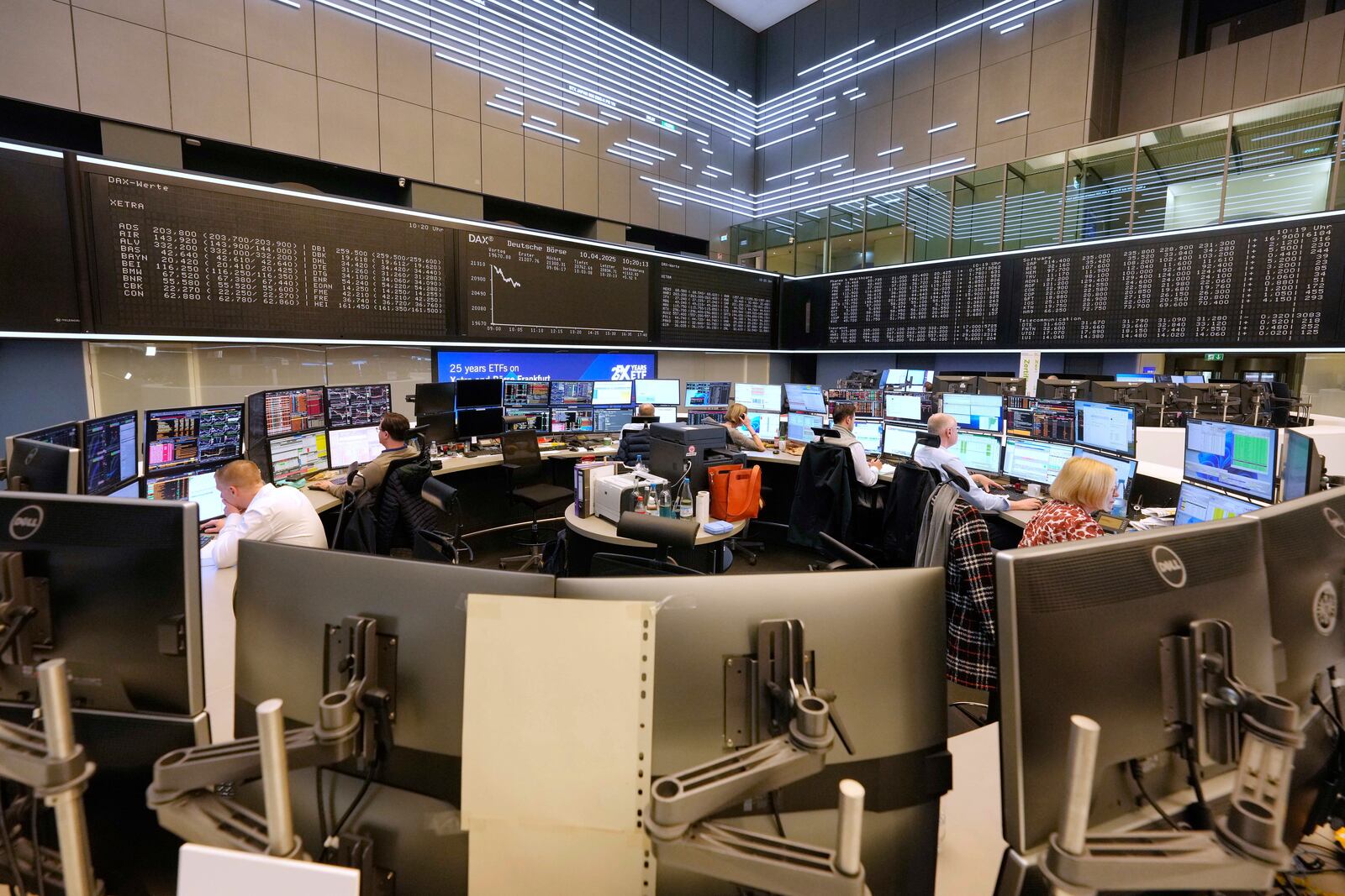 Traders work on the trading floor of the Frankfurt Stock Exchange in front of a display board showing the DAX stock index in Frankfurt, Germany, the day after U.S. President Donald Trump announced a 90-day pause on 'reciprocal' tariffs, Thursday, April 10, 2025. (AP Photo/Martin Meissner)