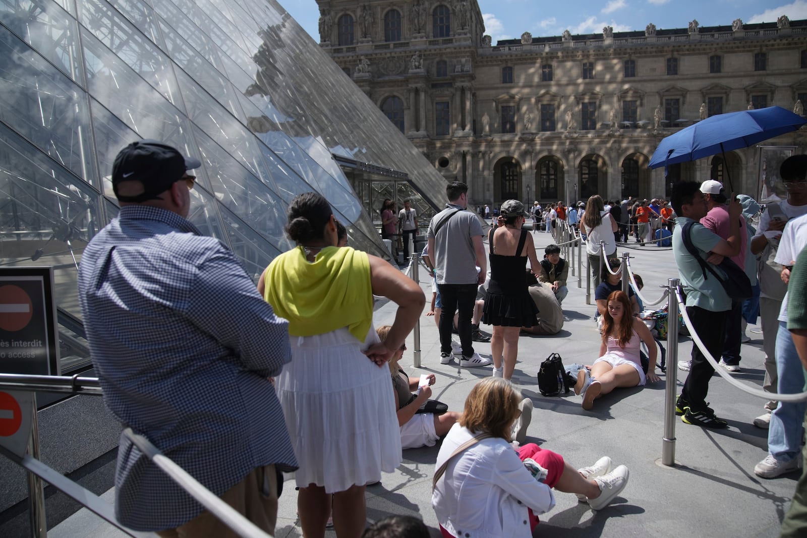 Tourists wait outside the Louvre museum which failed to open on time Monday, June 16, 2025 in Paris. (AP Photo/Christophe Ena)