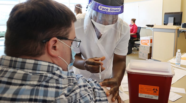 Vivian Adu, a nursing student at Clark State College, gives Andrew Deans a COVID vaccine injection during a clinic at the college a few months ago. BILL LACKEY/STAFF