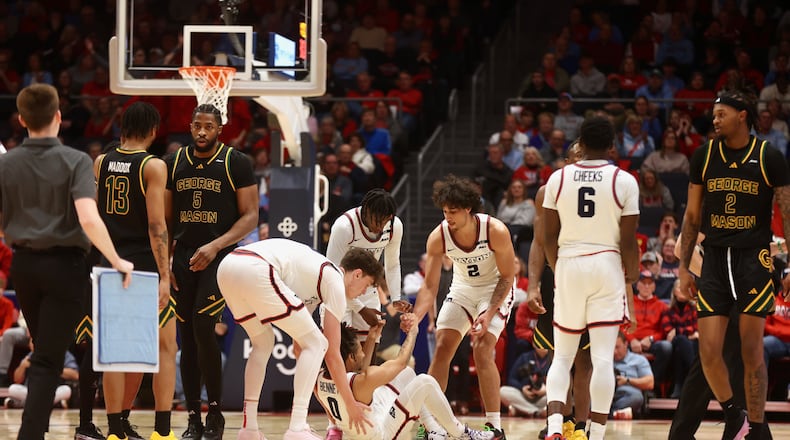 Dayton players help Javon Bennett get up during a game against George Mason on Wednesday, Jan. 15, 2025, at UD Arena. David Jablonski/Staff