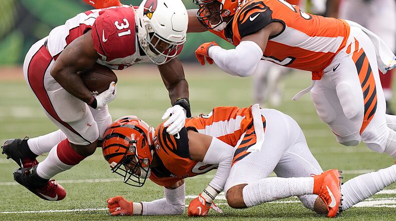 CINCINNATI, OHIO - OCTOBER 06: David Johnson #31 of the Arizona Cardinals is tackled by Preston Brown #52 and Jessie Bates #30 of the Cincinnati Bengals during the NFL football game at Paul Brown Stadium on October 06, 2019 in Cincinnati, Ohio. (Photo by Bryan Woolston/Getty Images)