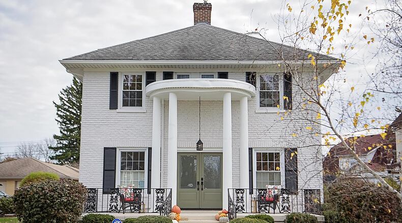 The front of the home has a two-story, covered entry with columns and a full front porch with wrought iron railings. CONTRIBUTED
