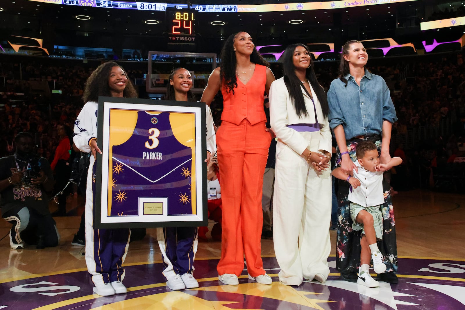 The jersey of former Los Angeles Sparks player Candace Parker, center, looks on with her family during her jersey retirement ceremony during a WNBA basketball game between the Sparks and the Chicago Sky, Sunday, June 29, 2025, in Los Angeles. (AP Photo/Jessie Alcheh)