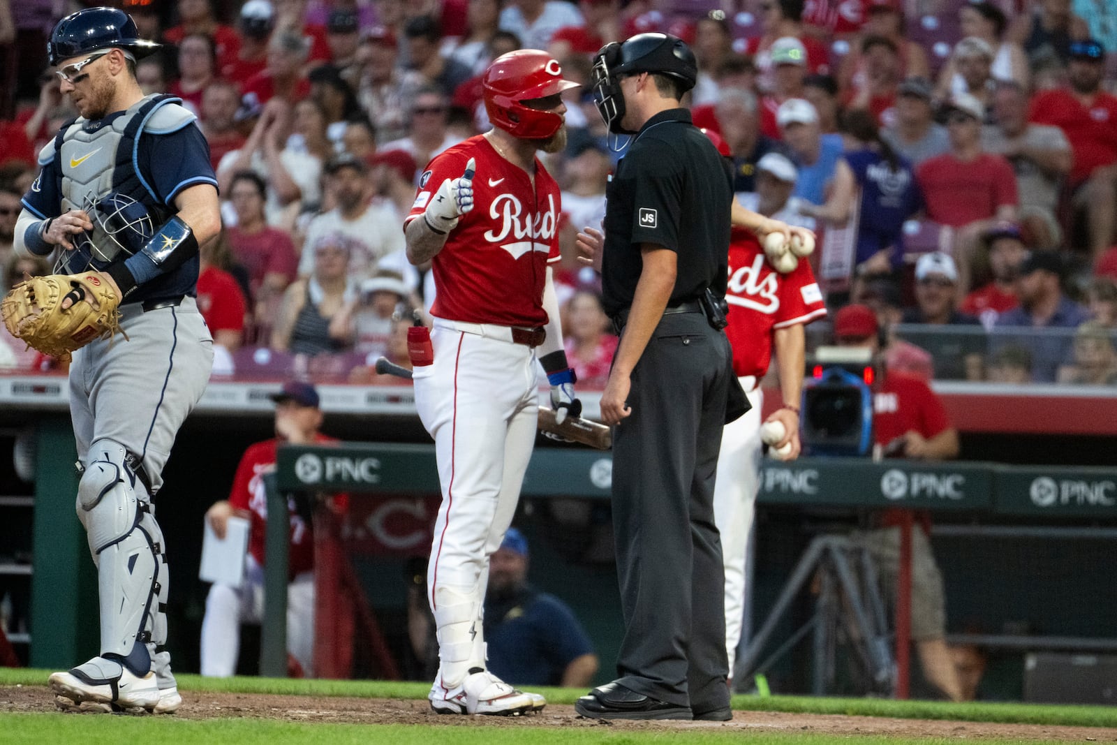 Cincinnati Reds' Jake Fraley, center left, argues with the umpire, center right, in the seventh inning against the Tampa Bay Rays, Saturday July 26, 2025, in Cincinnati. (AP Photo/Michael Swensen)