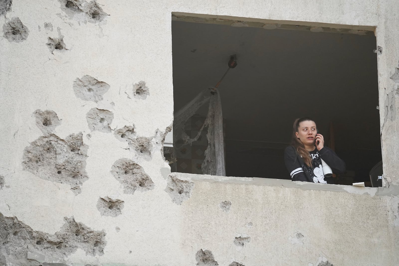 A woman looks though the window of her damaged apartment following a Russian strike in Kharkiv, Ukraine, Friday April 18, 2025. (AP Photo/Andrii Marienko)