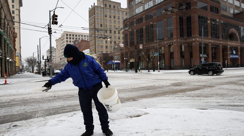 Downtown Dayton Partnership Ambassador Kalez Crise spreads ice melt on downtown sidewalk at Third and Main streets.