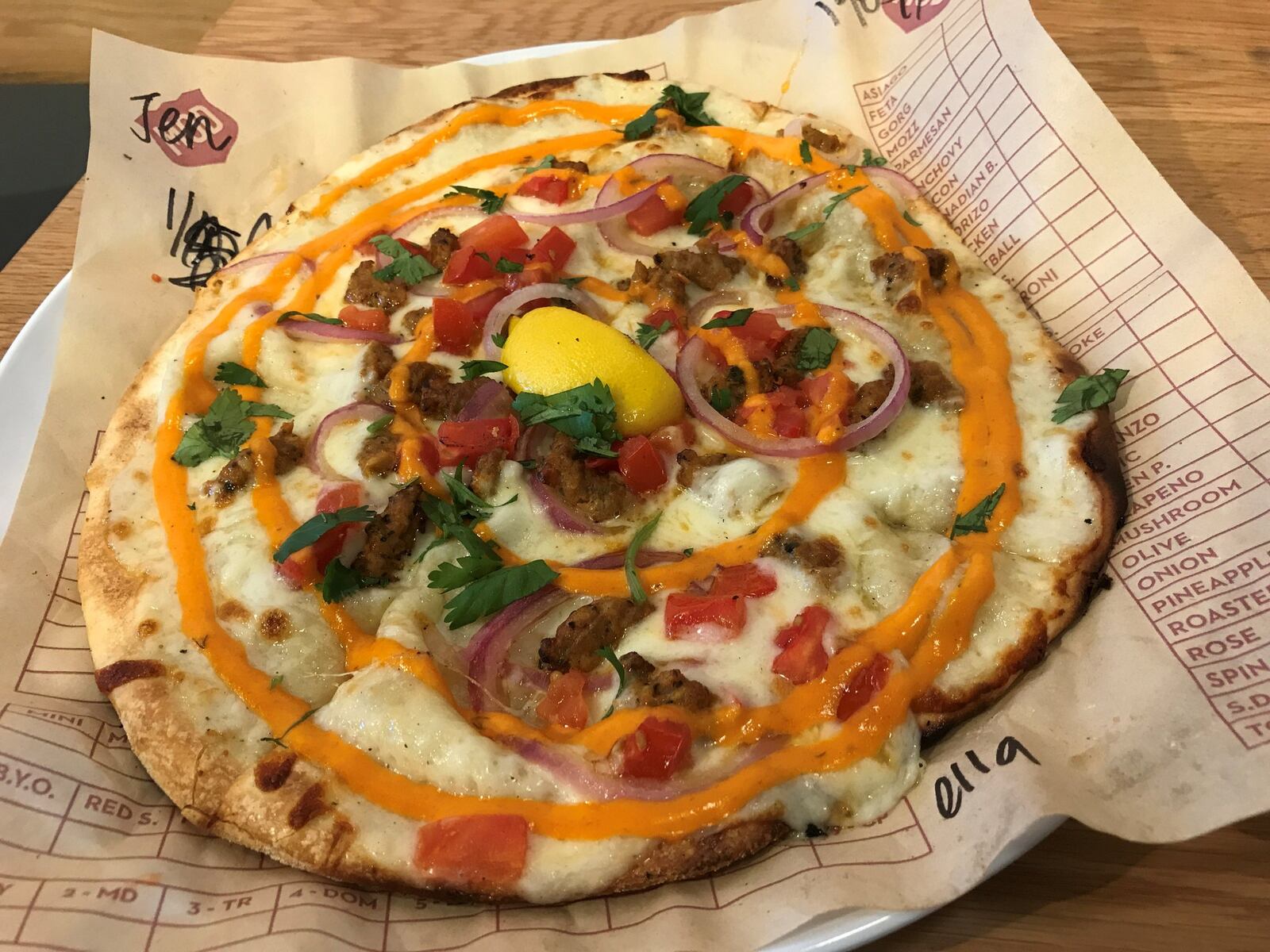 At MOD Pizza, you can build your own or try one of the restaurant’s creations, including a seasonal pie such as Ella (pictured) that holds white sauce, mozzarella, spicy chicken sausage, diced tomatoes, red onion, cilantro, a lemon wedge and Sriracha. LIGAYA FIGUERAS / LFIGUERAS@AJC.COM