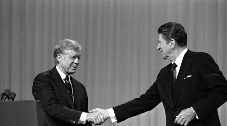 FILE - This Oct. 28, 1980 black-and-white file photo shows President Jimmy Carter, left, and Republican Presidential candidate Ronald Reagan shake hands after debating in the Cleveland Music Hall in Cleveland. In presidential politics, everybody’s searching for “the moment.” The campaigns don’t know when or how it will come, but they watch for something _ awkward words or an embarrassing image _ that can break through and become the defining symbol of the other guy’s flaws. Now all eyes are on the series of three presidential debates that starts Wednesday. (AP Photo/Madeline Drexler, File)