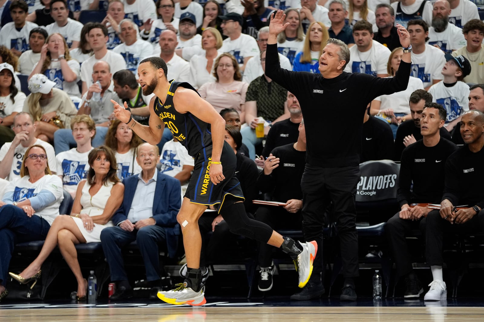 Golden State Warriors guard Stephen Curry (30), left, gestures after making a 3-point shot as Minnesota Timberwolves head coach Chris Finch, right, reacts during the first half of Game 1 of an NBA basketball second-round playoff series, Tuesday, May 6, 2025, in Minneapolis. (AP Photo/Abbie Parr)