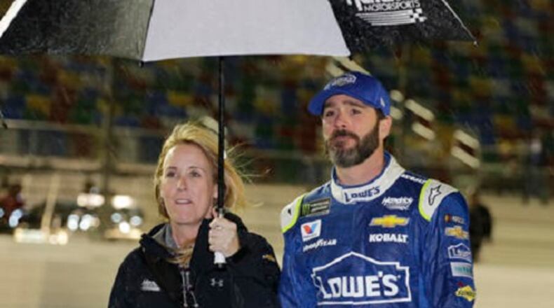Jimmie Johnson, right, takes shelter under an umbrella with a team member during a rain delay before the NASCAR Clash auto race at Daytona International Speedway, Saturday, Feb. 18, 2017, in Daytona Beach, Fla. (AP Photo/Terry Renna)
