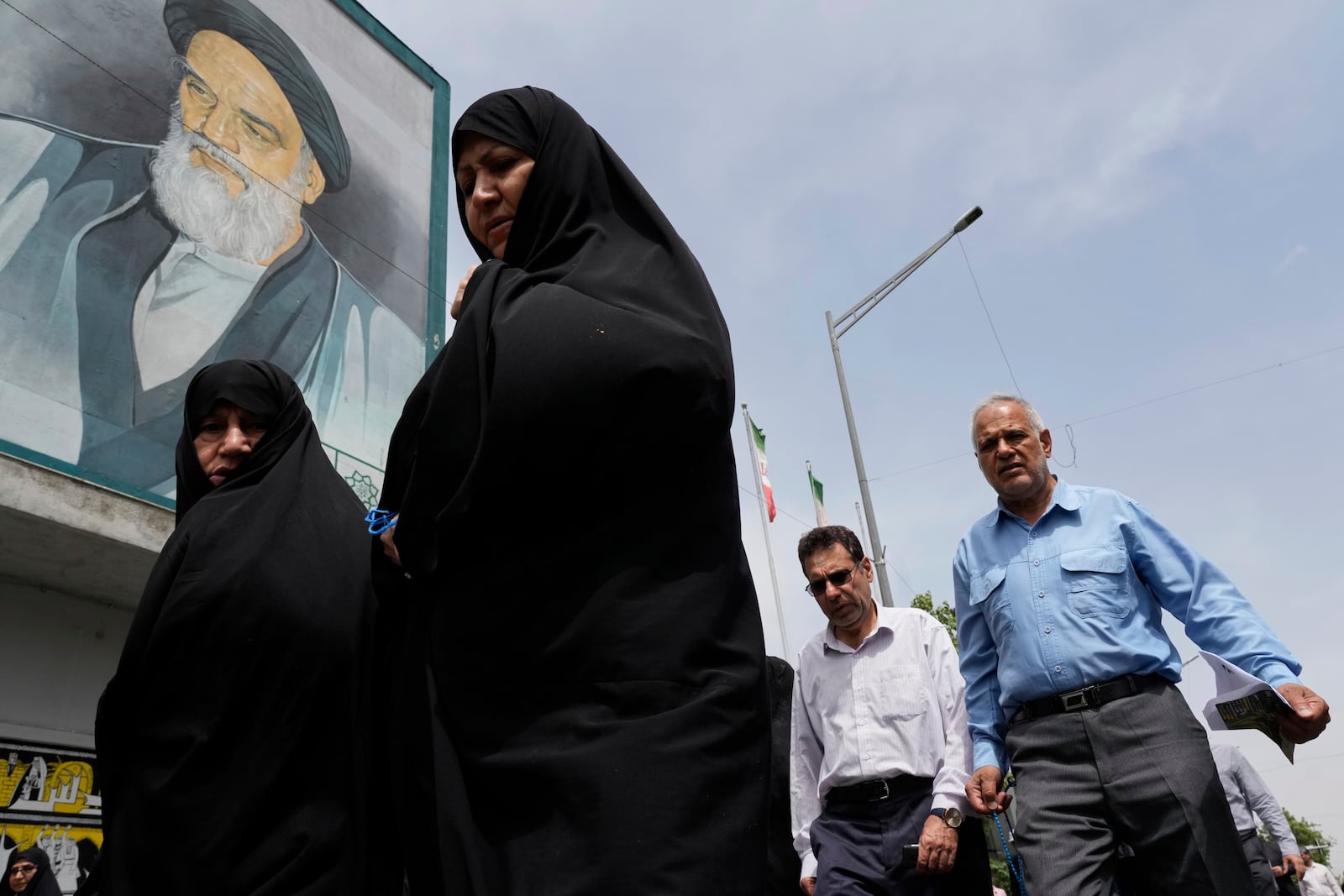 Worshippers walk under a mural of the late Iranian revolutionary founder Ayatollah Khomeini as they leave after the conclusion of the Friday prayer ceremony, in Tehran, Iran, Friday, April 25, 2025. (AP Photo/Vahid Salemi)