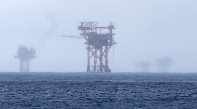 FILE - Oil platforms are visible through the haze near the Flower Garden Banks National Marine Sanctuary in the Gulf of Mexico, off the coast of Galveston, Texas, Sept. 16, 2023. (AP Photo/LM Otero, File)