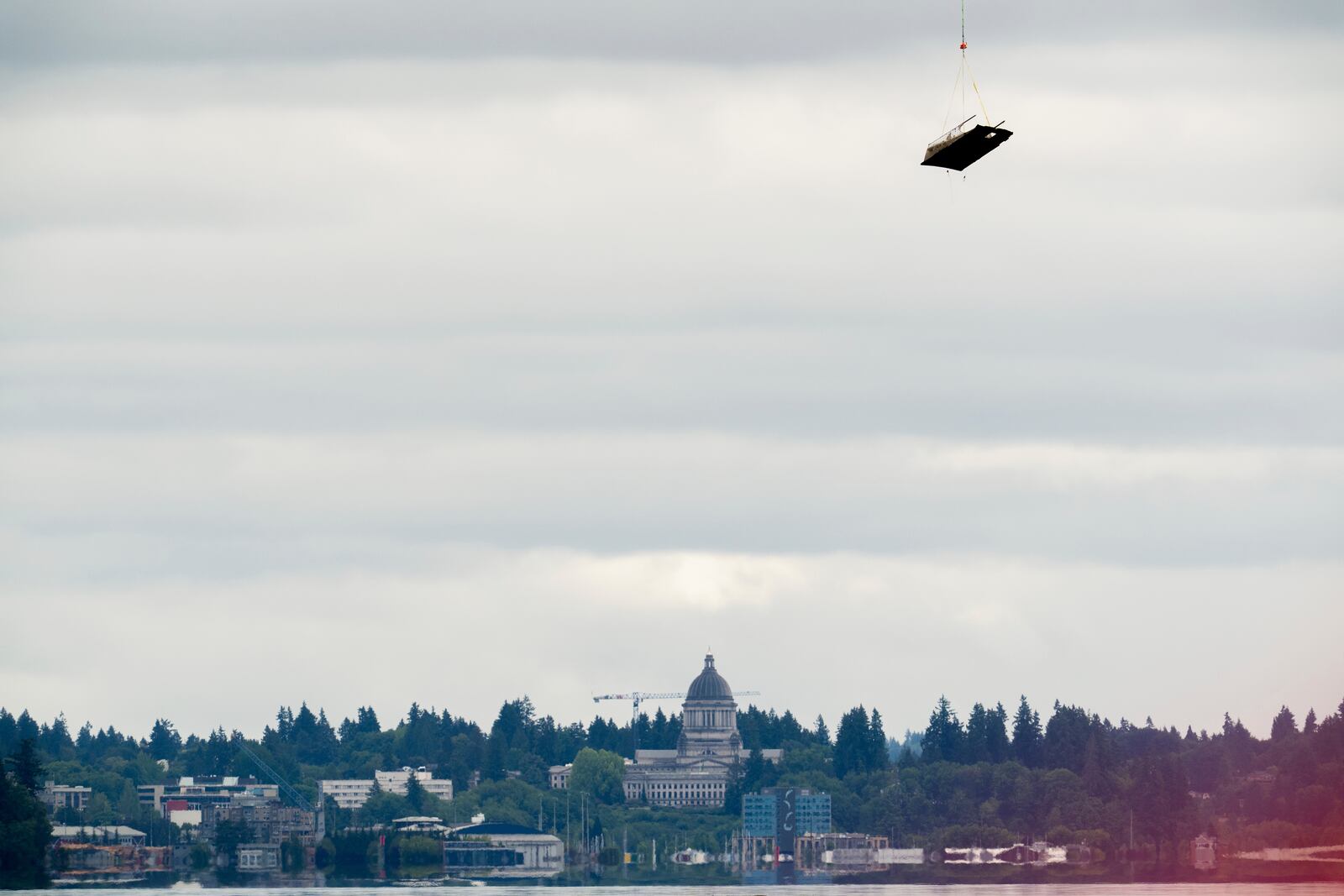 With the Washington Capitol building in the background, an abandoned ship is airlifted on Wednesday, June 4, 2025, in Olympia, Wash. (AP Photo/Jenny Kane)