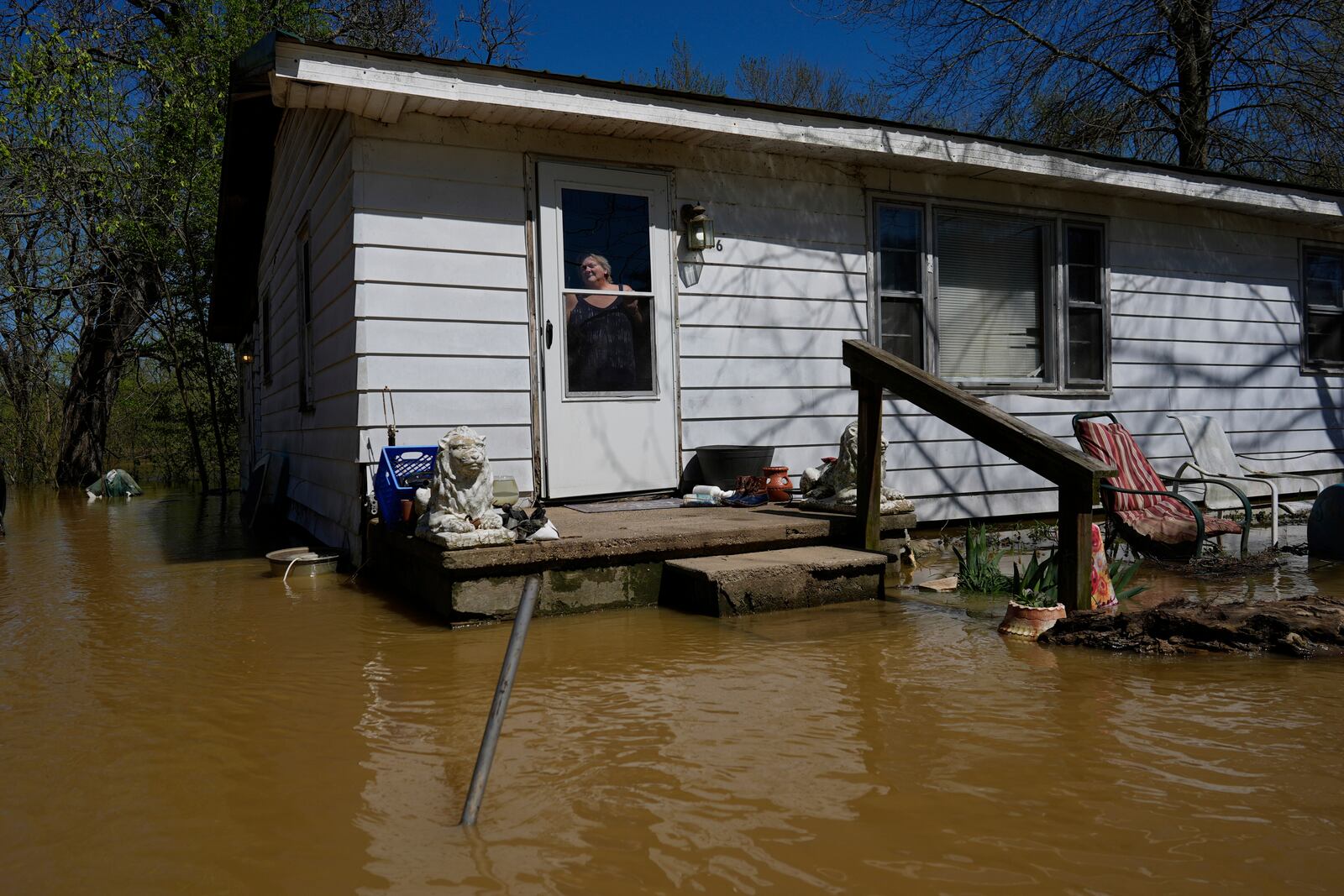 Glenda Lyons looks out from Lockport, Ky., home surrounded by Kentucky River floodwaters, Tuesday, April 8, 2025. (AP Photo/Carolyn Kaster)