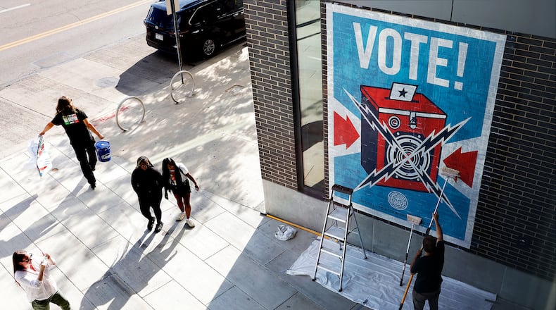 Artist Shepard Fairey places a mural Wednesday, Sept. 18, 2024, on the Dayton Metro Library Downtown. MARSHALL GORBY\STAFF